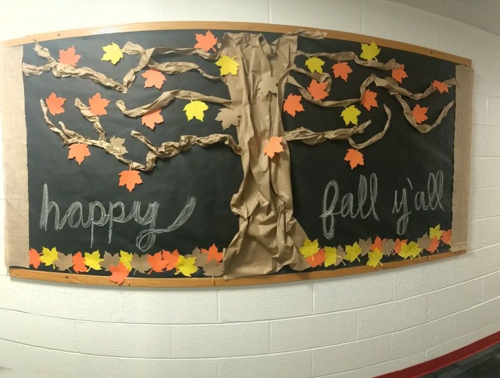 Decorative bulletin board featuring a tree with colorful leaves and the text 'happy fall y'all'.