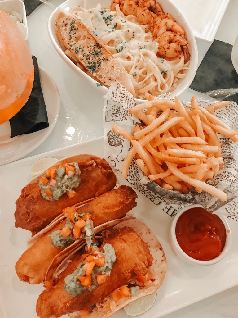 table of food ordered at the sugar factory in biloxi, ms, including fish tacos, fries, shrimp alfredo and goblet at the sugar factory 