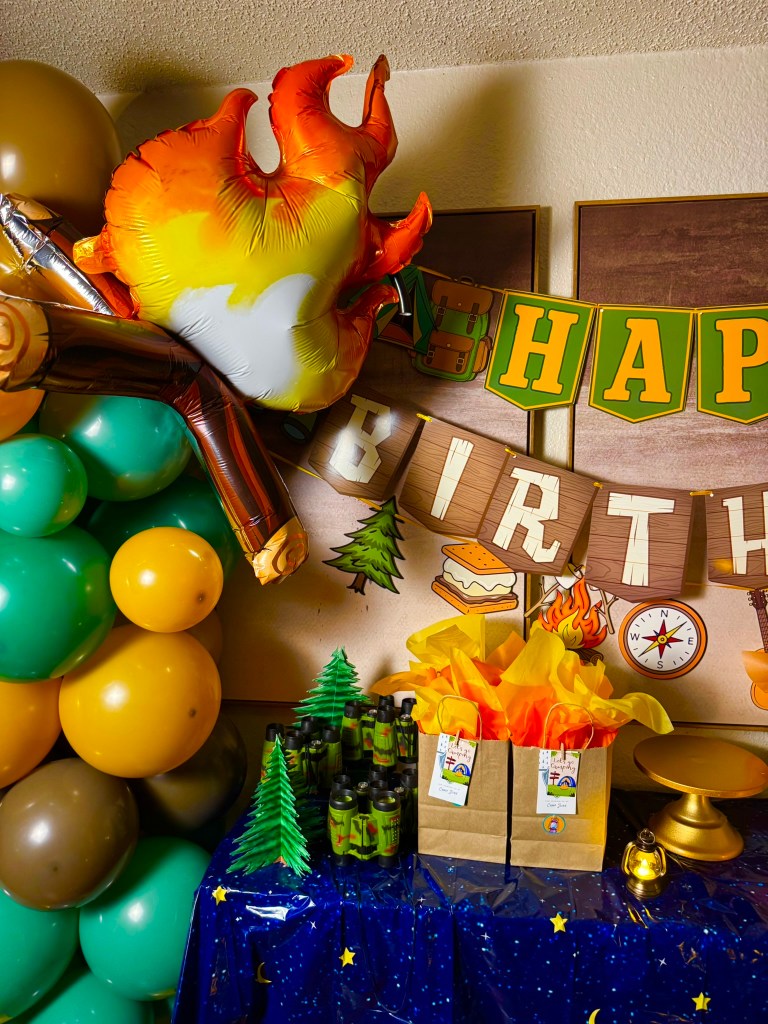 Kids camping party goodie bags with orange and yellow tissue paper and outdoor adventure tags.
