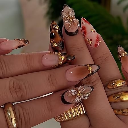 Close-up of beautifully manicured nails featuring a mix of glossy and matte finishes, adorned with intricate floral designs and golden embellishments, showcasing a blend of earth tones and artistic detailing.