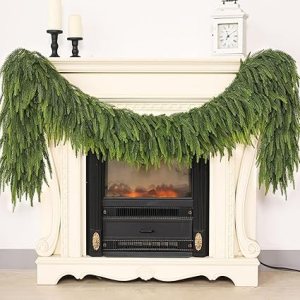A lush green garland draped over a white fireplace mantle, with a faux fire glowing below.