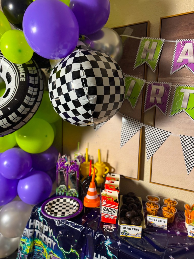Monster Jam birthday party setup with racing themed decorations, checkered balloons, dessert table, and monster truck party supplies.