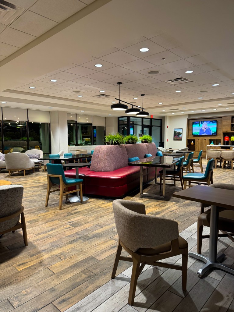 Spacious lobby seating area with tables, chairs and colorful booths at Home2 Suites Pigeon Forge.