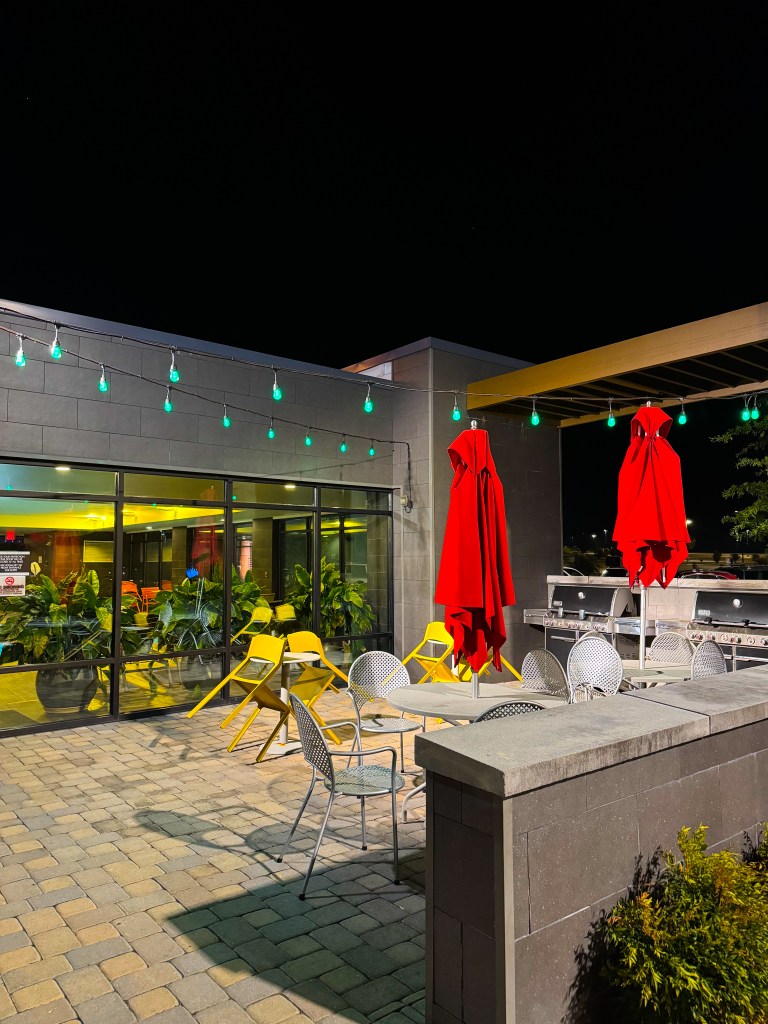 Outdoor patio with grills, tables and umbrellas at Home2 Suites Pigeon Forge.