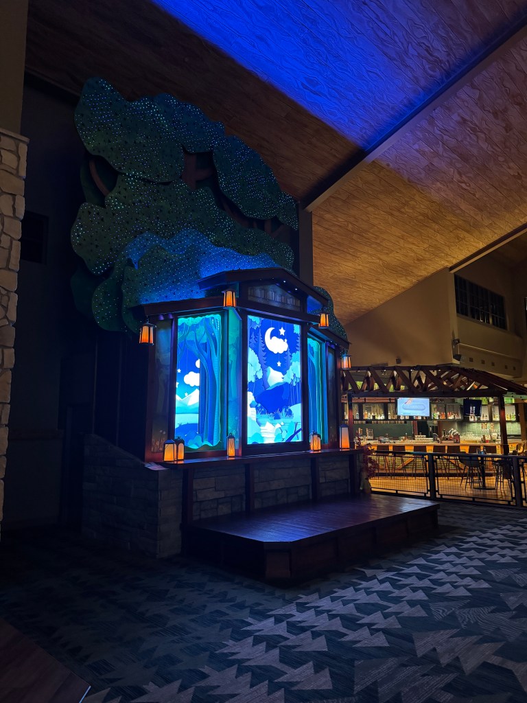 Interior view of Great Wolf Lodge showing a decorative tree structure with colorful backlighting, and a cozy seating area in the lobby.