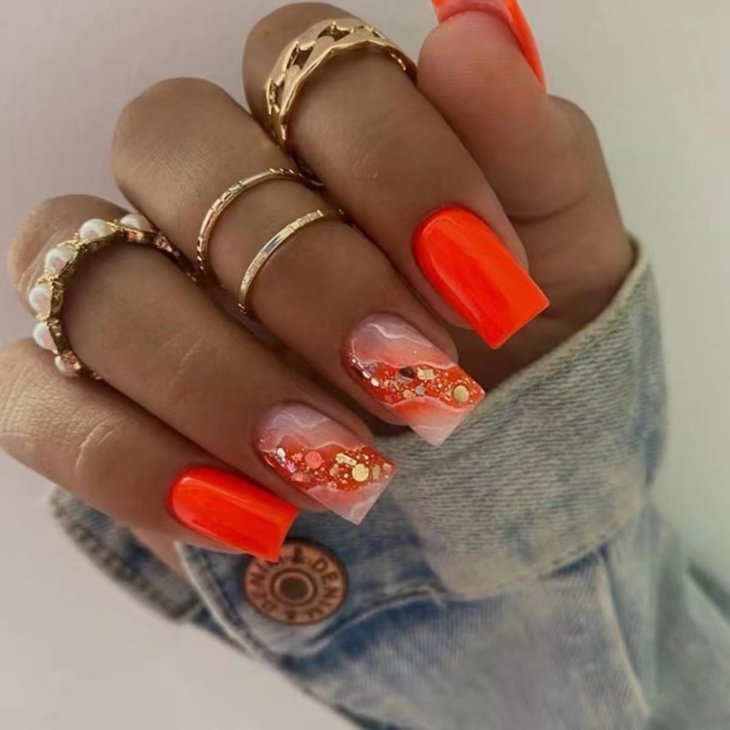 Bright neon orange square acrylic nails with glitter wave accents over a nude base