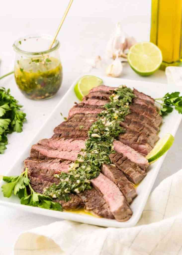 Chimichurri steak topped with fresh herby sauce for a flavorful summer grilling recipe.