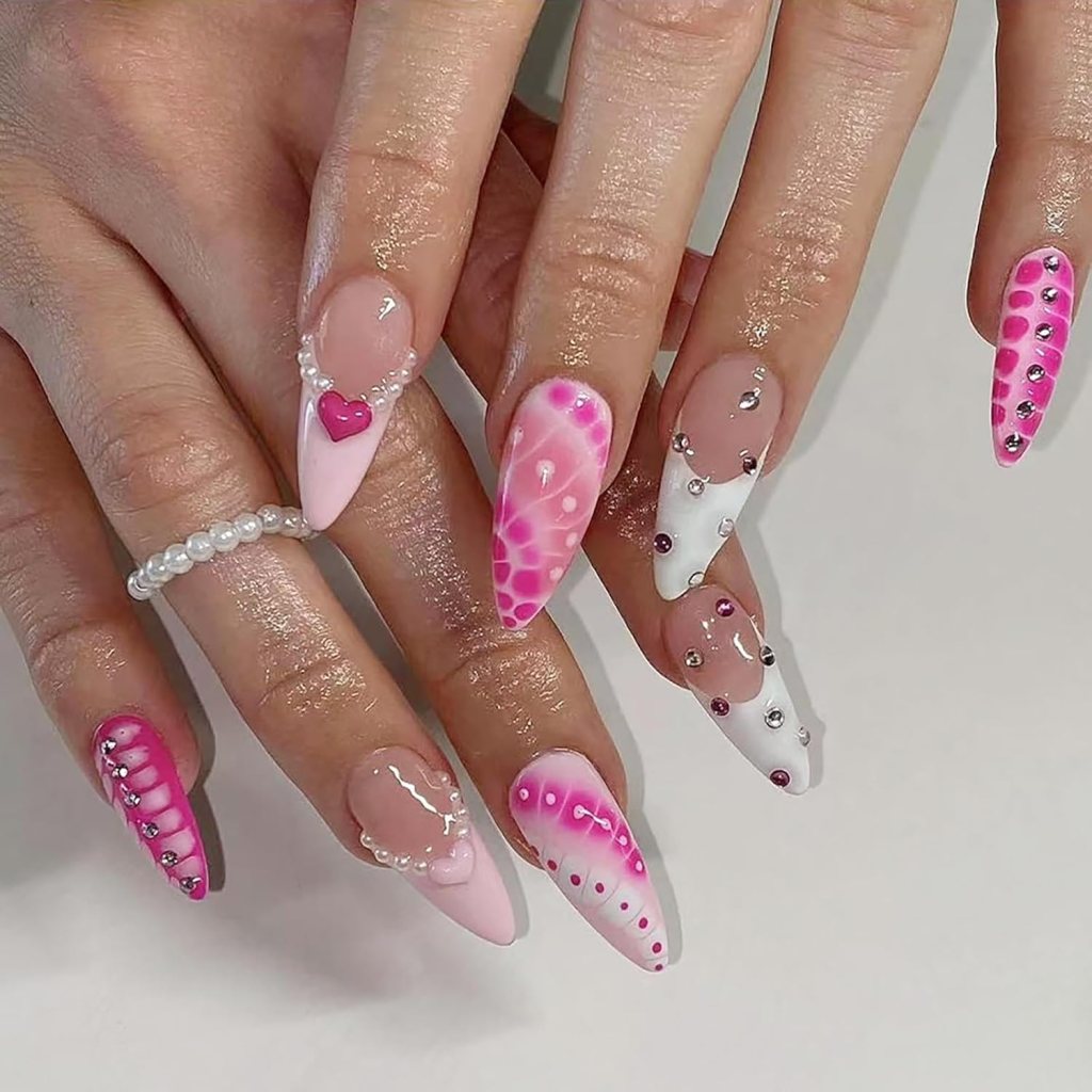 Close-up of manicured hands with long, colorful nails featuring pink shades, intricate designs, and embellishments like pearls and rhinestones.