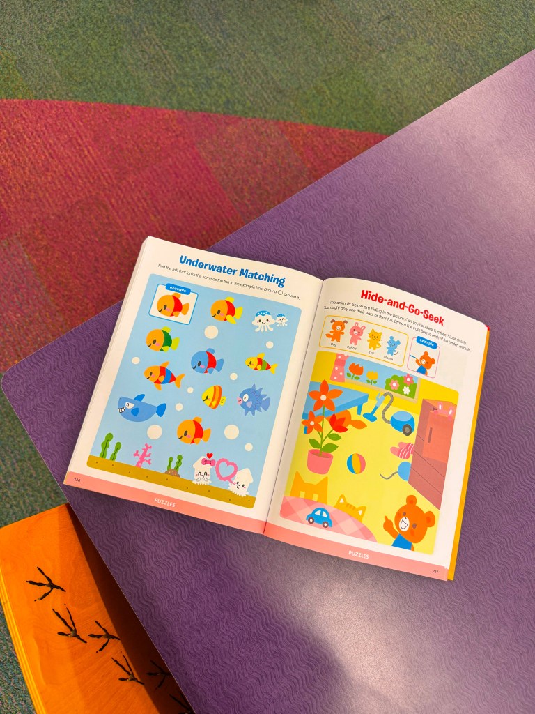 An open children's activity book featuring two pages: 'Underwater Matching' with colorful fish and 'Hide-and-Go-Seek' with playful animals and objects on a vibrant background.