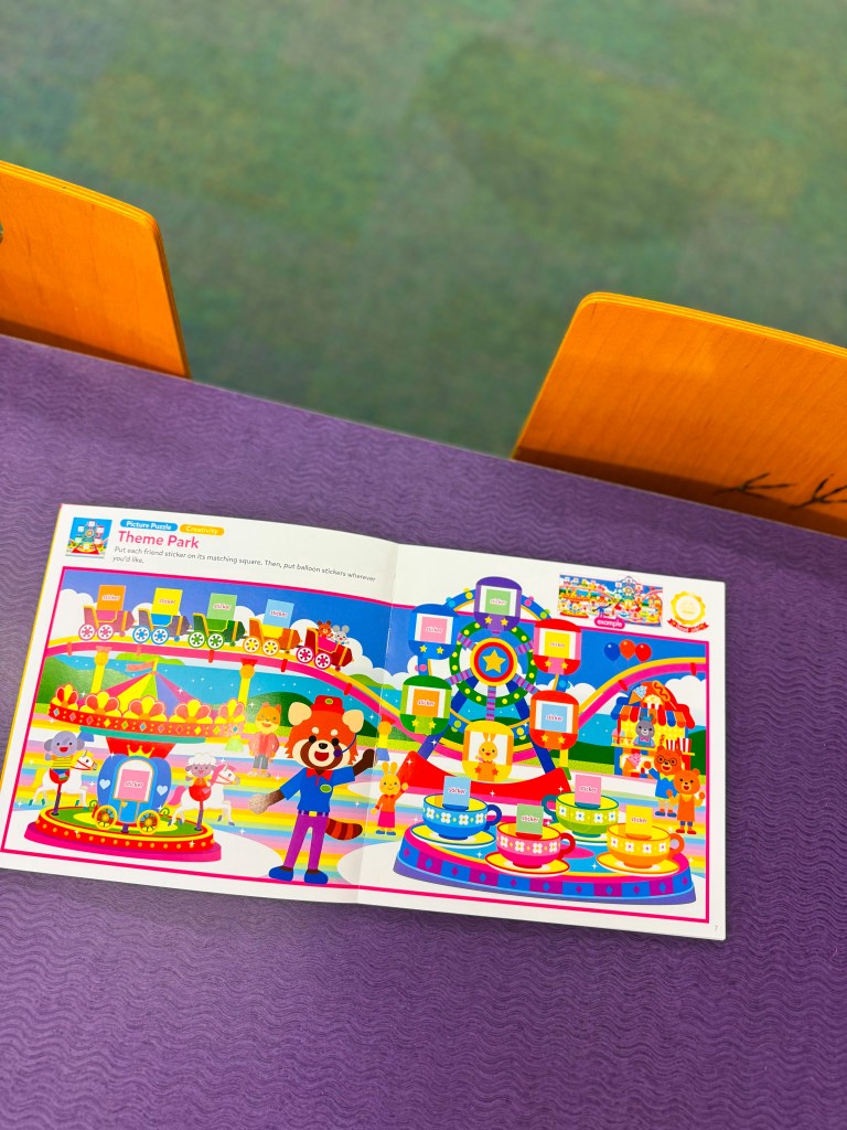 A colorful theme park map featuring cartoon animals, attractions, and interactive areas, placed on a purple table.