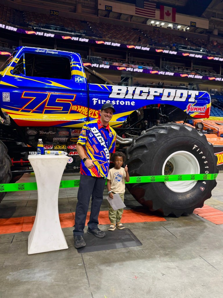 Young child poses with the Bigfoot driver beside the blue monster truck.