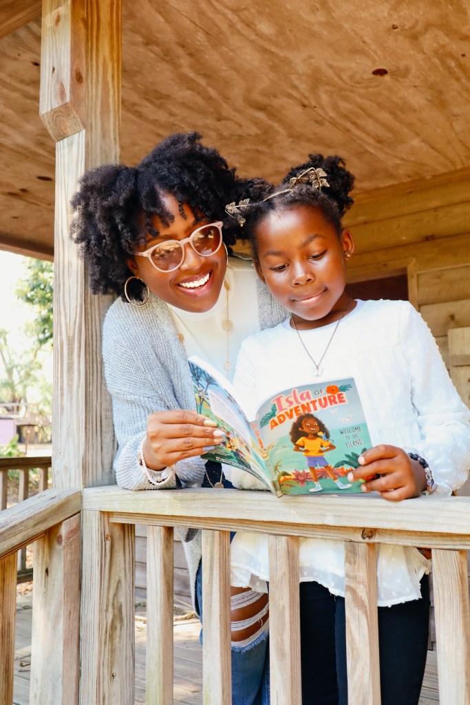 Young girl smiling while reading a Mia Mayhem chapter book inside a colorful reading space.
