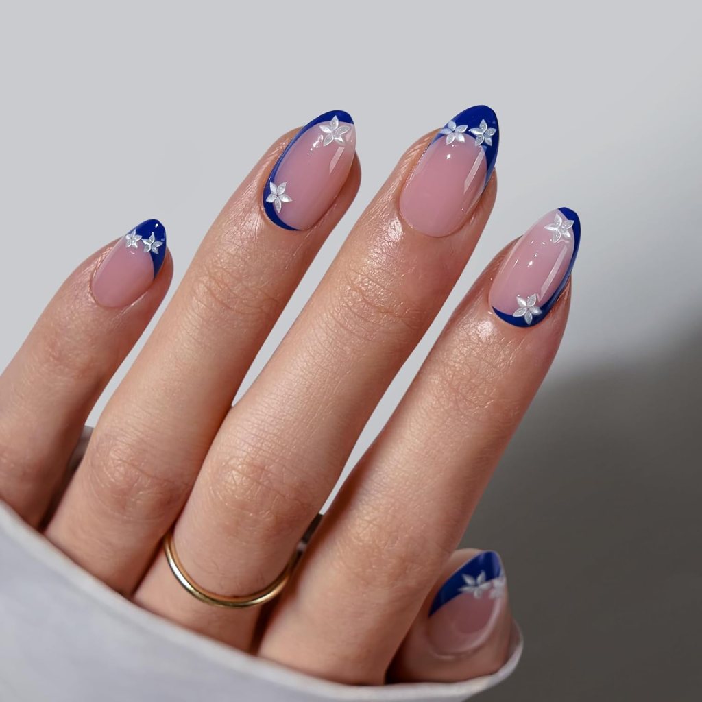 Blue floral French tip almond nails with delicate white flowers and glossy cobalt blue French tips.