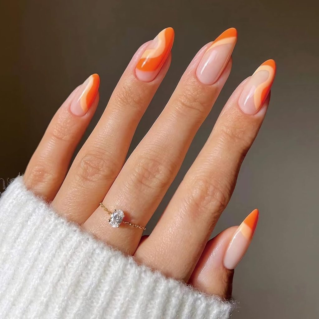 Almond nails with nude base and orange swirl French tip design with layered tones