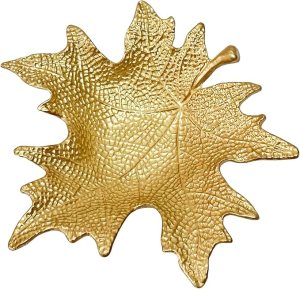 A decorative gold leaf dish, shaped like a maple leaf, ideal for autumn-themed table settings.