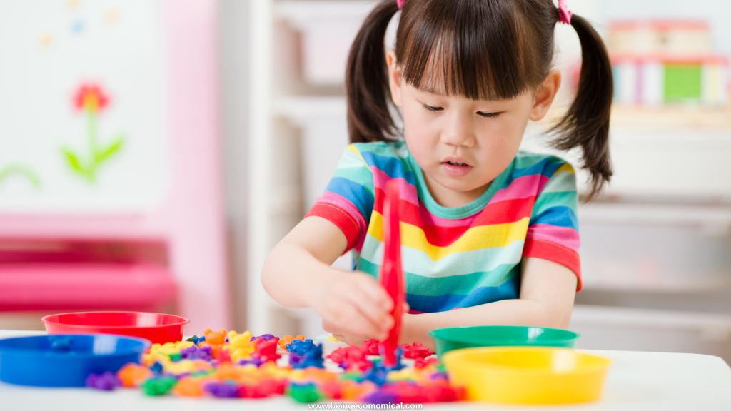 Preschooler sorting colorful objects with tongs during a fine motor homeschool preschool activity.