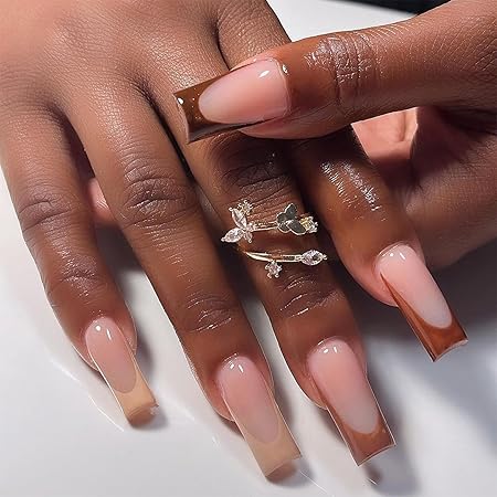 A close-up of well-manicured hands showcasing long, square-shaped nails with a gradient effect from nude to deep brown, adorned with delicate silver rings.