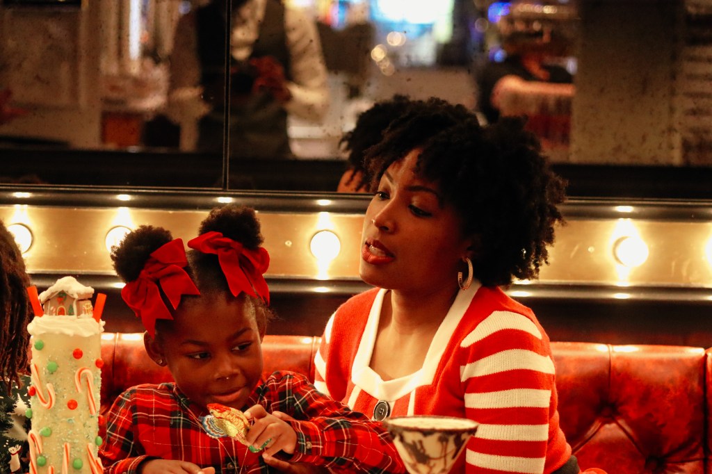 Mother and daughter smiling together at a table inside Sugar Factory Biloxi during a Christmas family getaway.