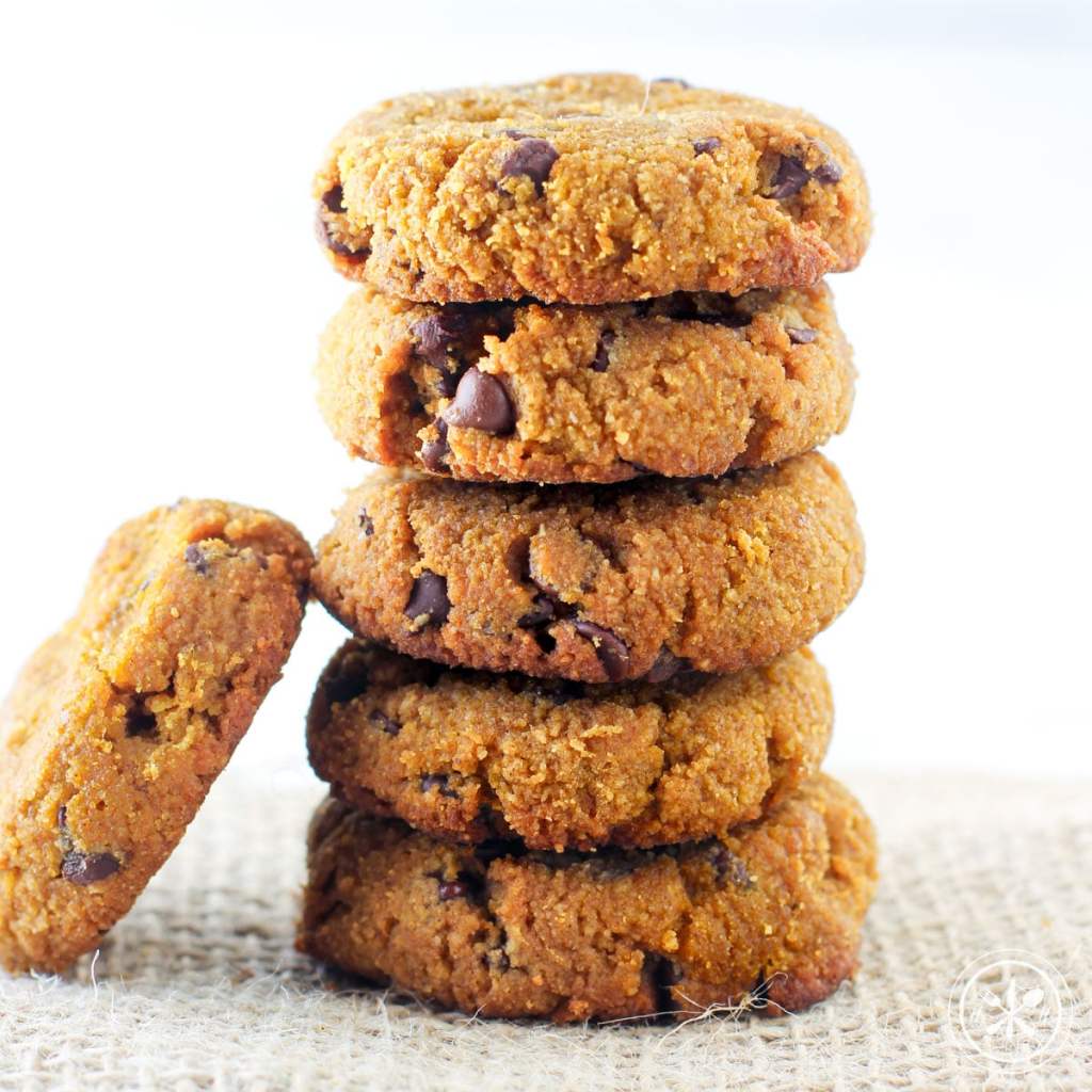 A stack of pumpkin chocolate chip cookies resting on a textured surface, showcasing their golden-brown color and chocolate chip inclusions.