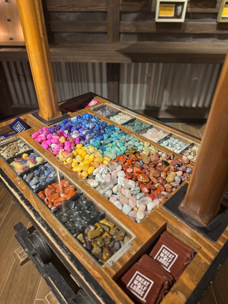A display of colorful gemstones and minerals at Great Wolf Lodge, showcasing a variety of stones in vibrant hues lined in a wooden container.