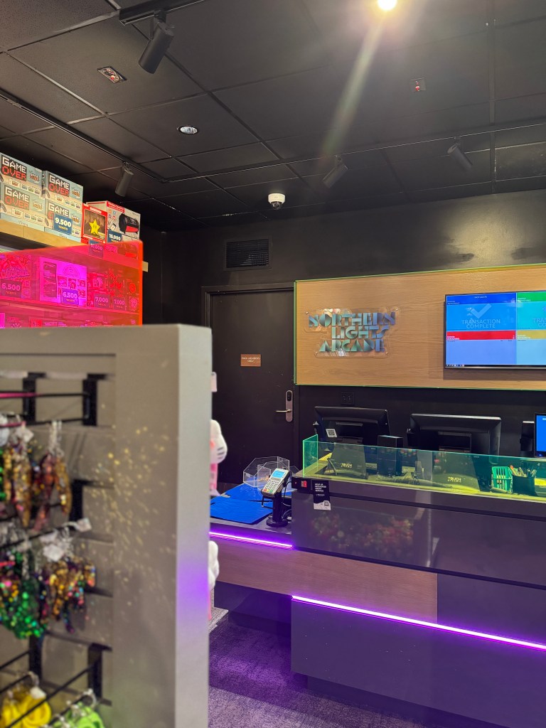 Interior view of the Northern Lights Arcade at Great Wolf Lodge featuring counters, arcade game prizes, and electronic payment displays.