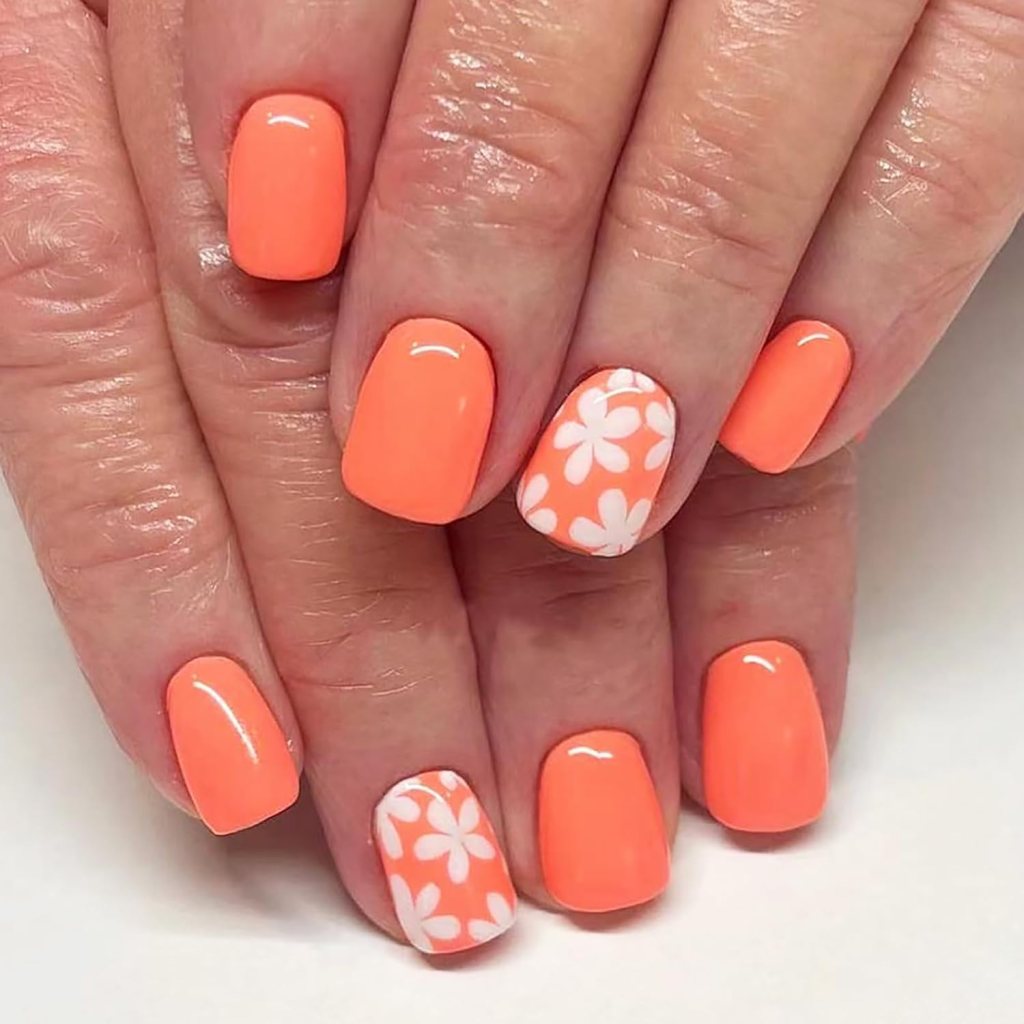Short orange nails with white floral accent nail and glossy finish