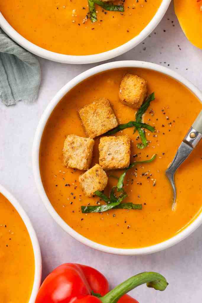 Creamy butternut squash soup topped with crunchy croutons and fresh herbs served in a rustic bowl