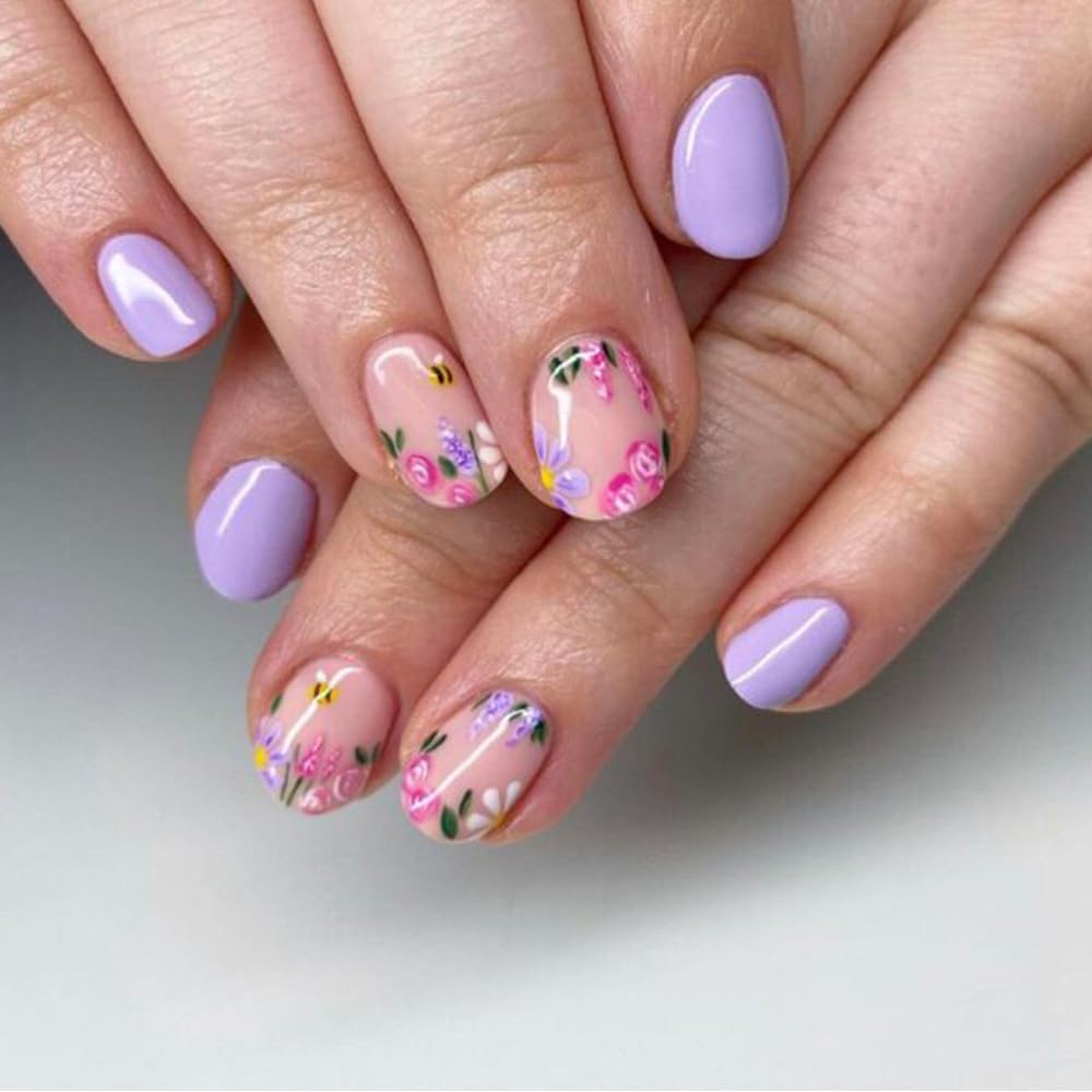 Close-up of beautifully manicured hands with lavender nails and floral designs on some nails.