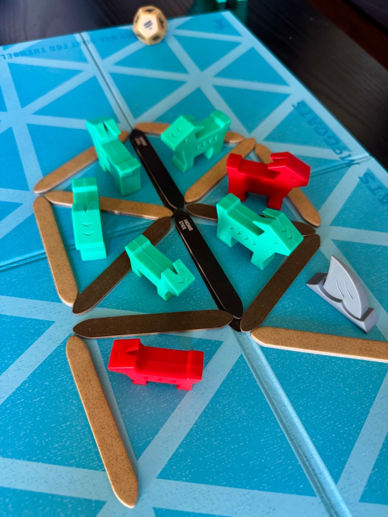 A close-up view of a board game setup featuring colorful game pieces in green and red, arranged on a blue game board with multiple intersecting lines.