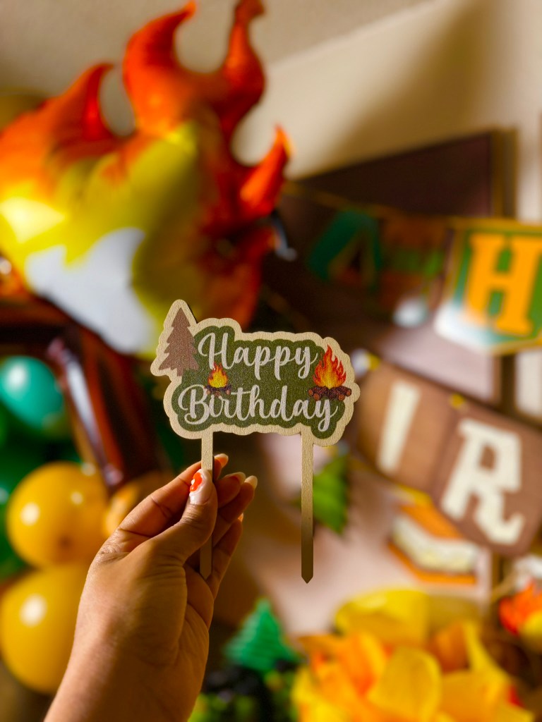 Camping themed second birthday cake with woodland cake topper and cozy lantern lights.