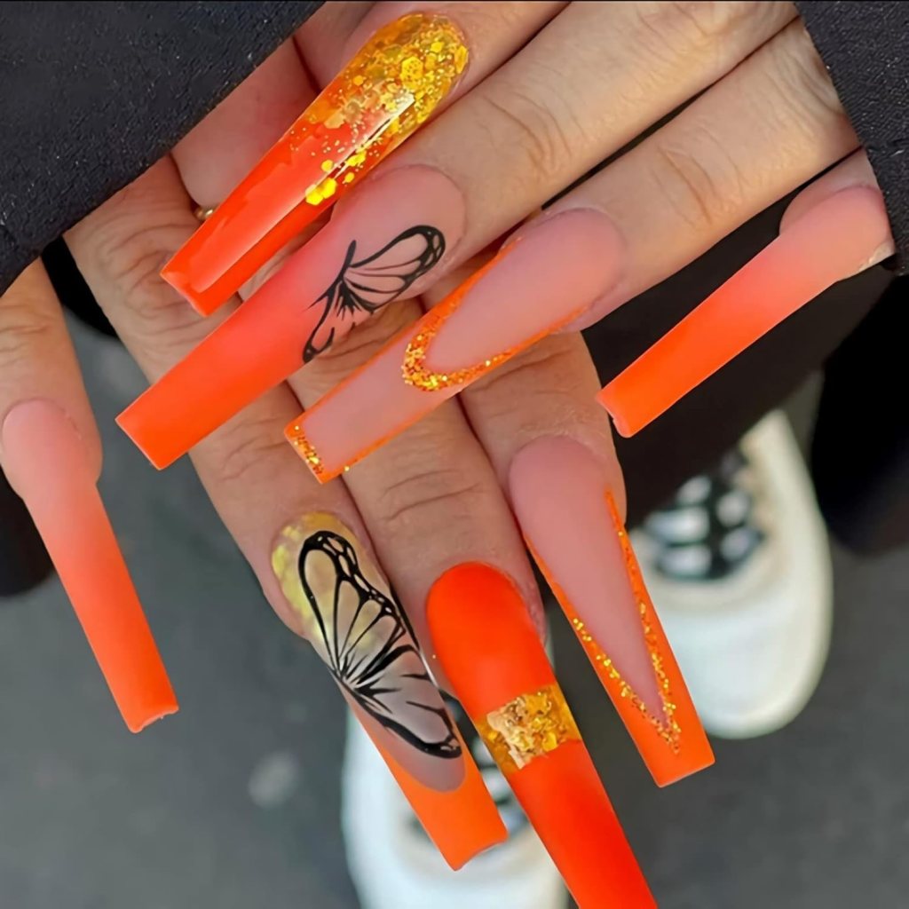 Long coffin nails with orange ombre gradient and butterfly nail art details