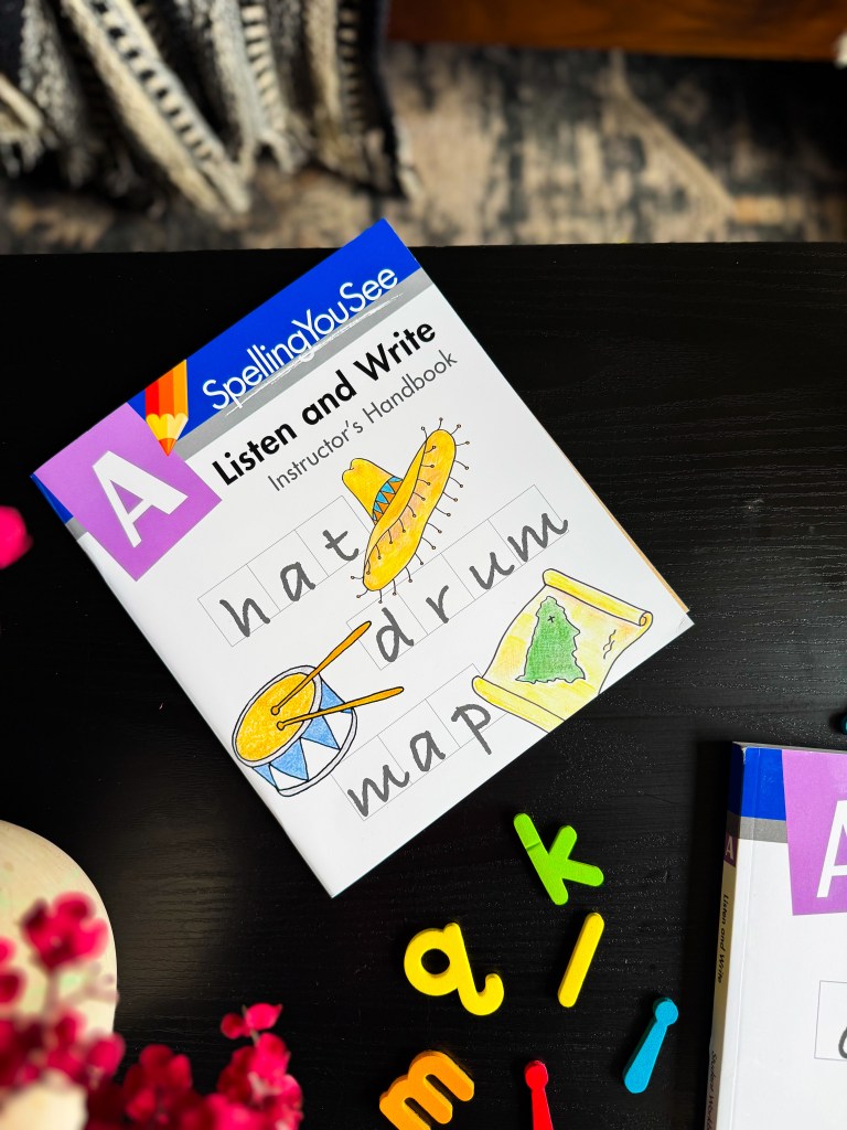 Close-up of the Spelling You See Level A instructor's handbook featuring illustrated words and beginner spelling examples.