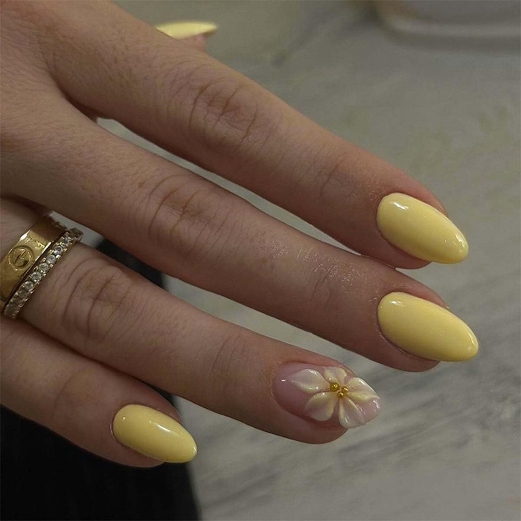Butter yellow almond nails with delicate flower accent nail art and glossy pastel manicure finish