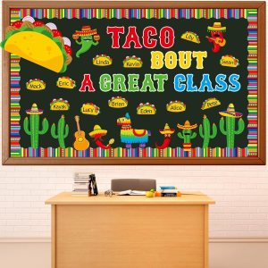 Classroom bulletin board with a colorful taco theme, featuring the words 'Taco Bout A Great Class' and images of tacos, cacti, and a piñata. Names of students are displayed on labels around the board.