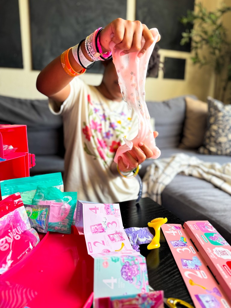 Tween girl stretching and customizing Gui Gui slime with colorful mix-ins as a creative Christmas gift activity for girls ages 8 to 12.