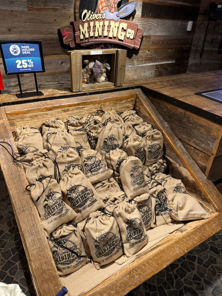 Oliver’s Mining Co. gem mining bags at Great Wolf Lodge Grapevine with a pass holder discount sign nearby.