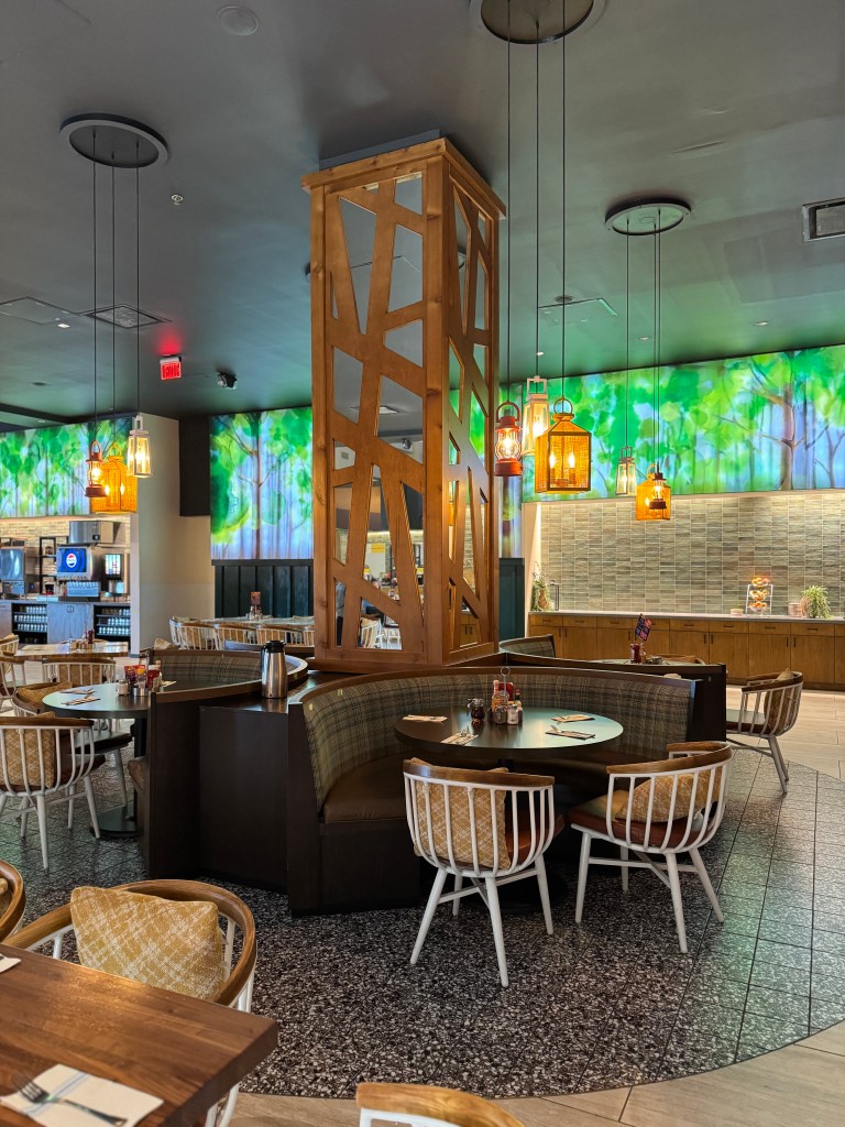 Interior view of a restaurant with wooden accents, modern seating, and vibrant, nature-themed wall art.