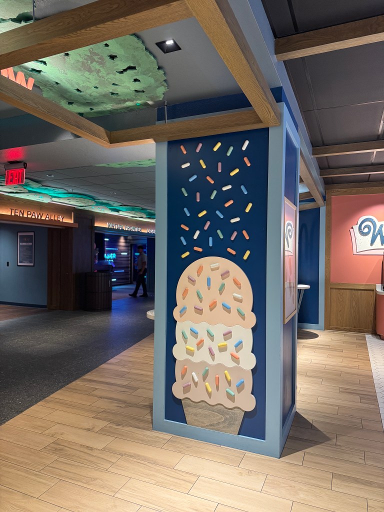 A playful ice cream cone mural with colorful sprinkles on a wall in the lobby area of Great Wolf Lodge in Grapevine, TX, showcasing a fun and family-friendly atmosphere.