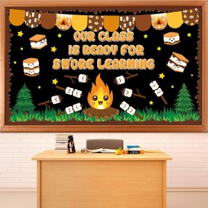 Classroom bulletin board featuring a campfire theme with the text 'Our class is ready for S'more learning,' decorated with marshmallows, stars, and trees.