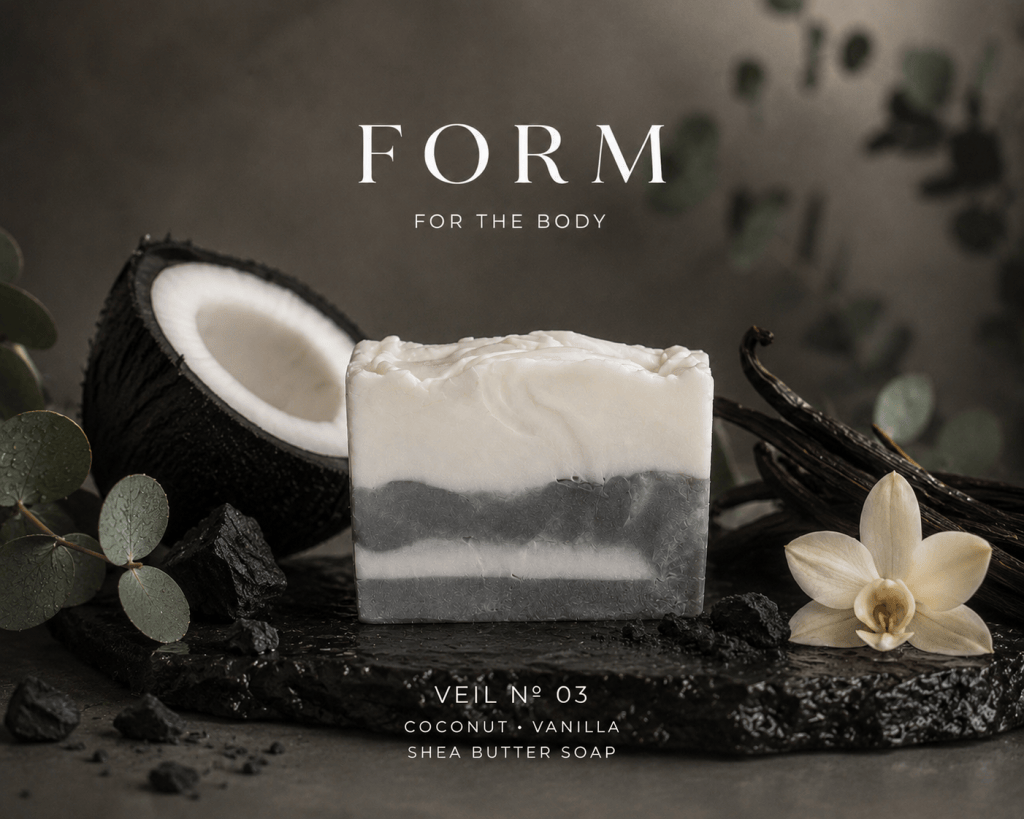 A bar of coconut and vanilla shea butter soap, featuring a layered design with white and gray swirls, placed on a dark stone surface. Fresh coconut and vanilla flowers are included in the composition.