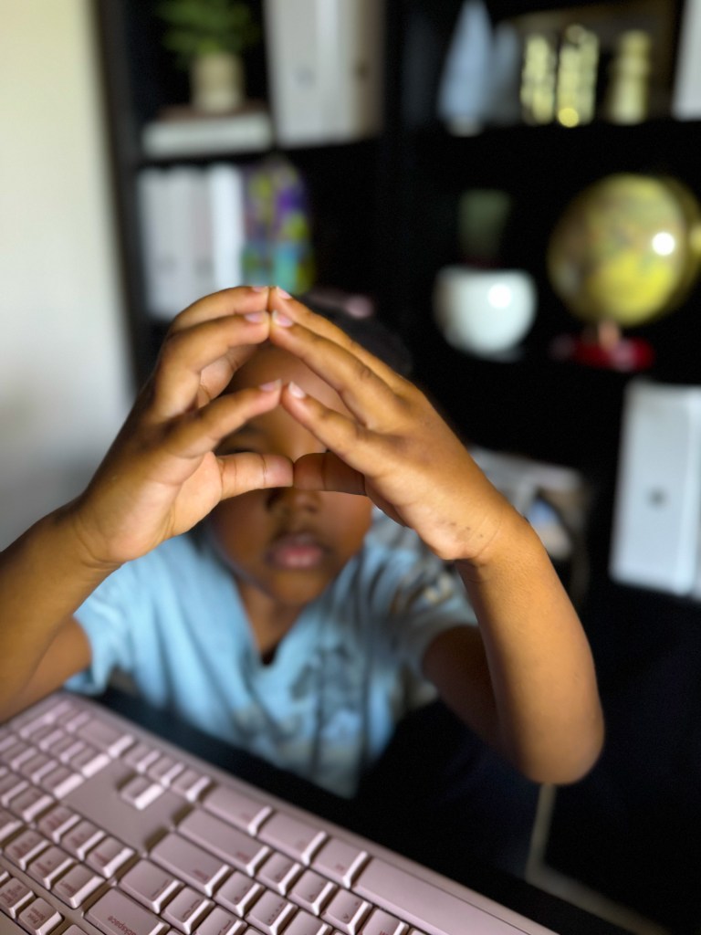 Child forming a shape with his hands during a movement-based kindergarten learning activity