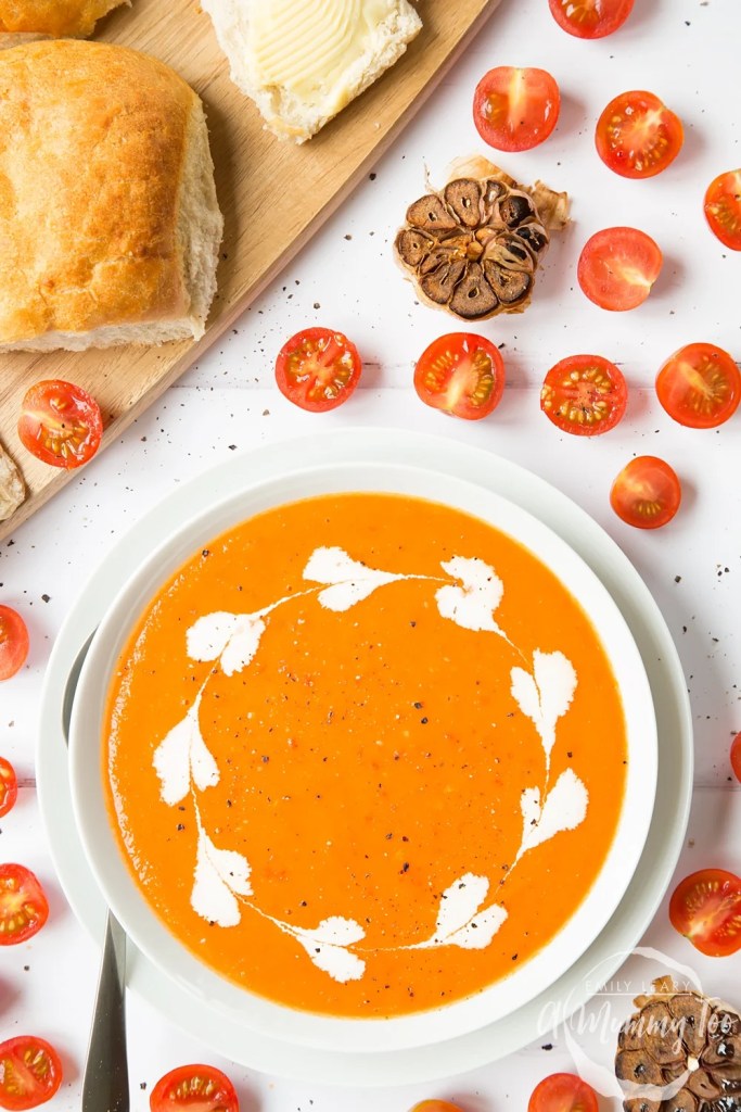 Homemade roasted tomato and garlic soup topped with fresh herbs in a ceramic bowl