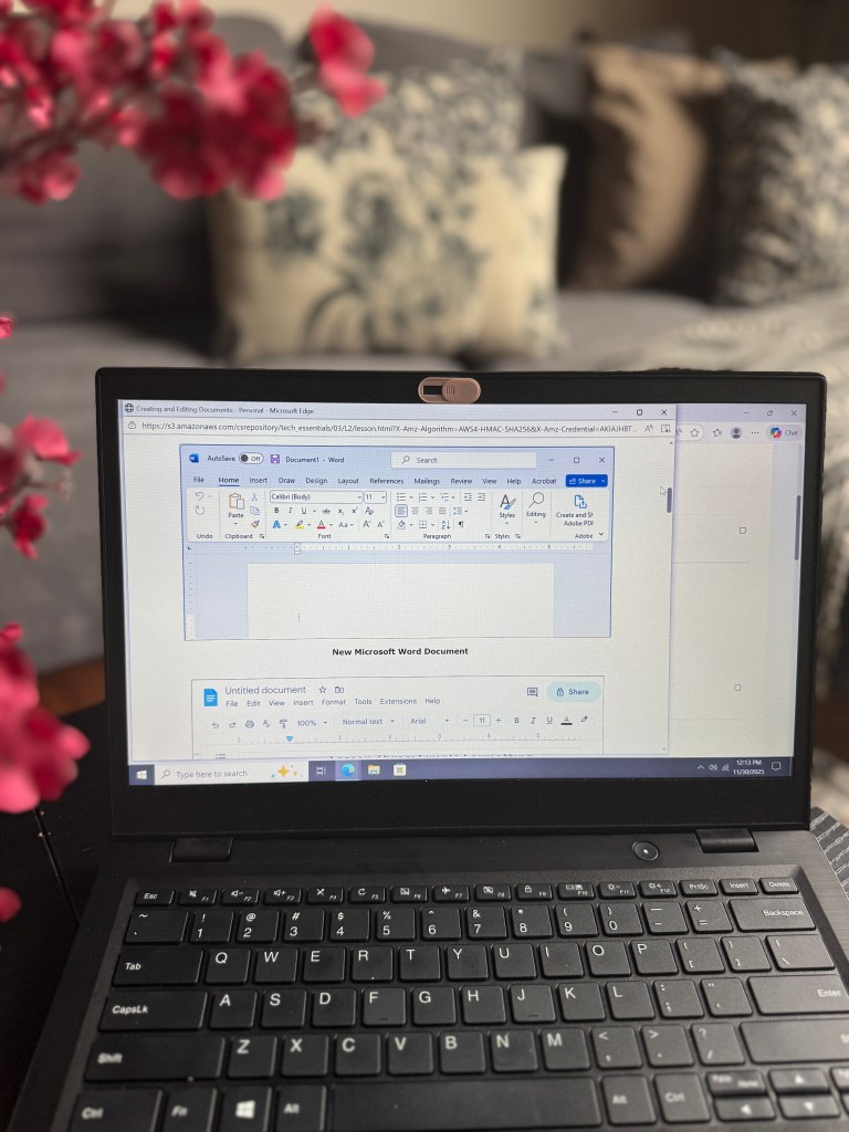 A laptop displaying a Microsoft Word document titled 'New Microsoft Word Document' with a keyboard visible and a blurred background featuring decorative pillows and pink flowers.