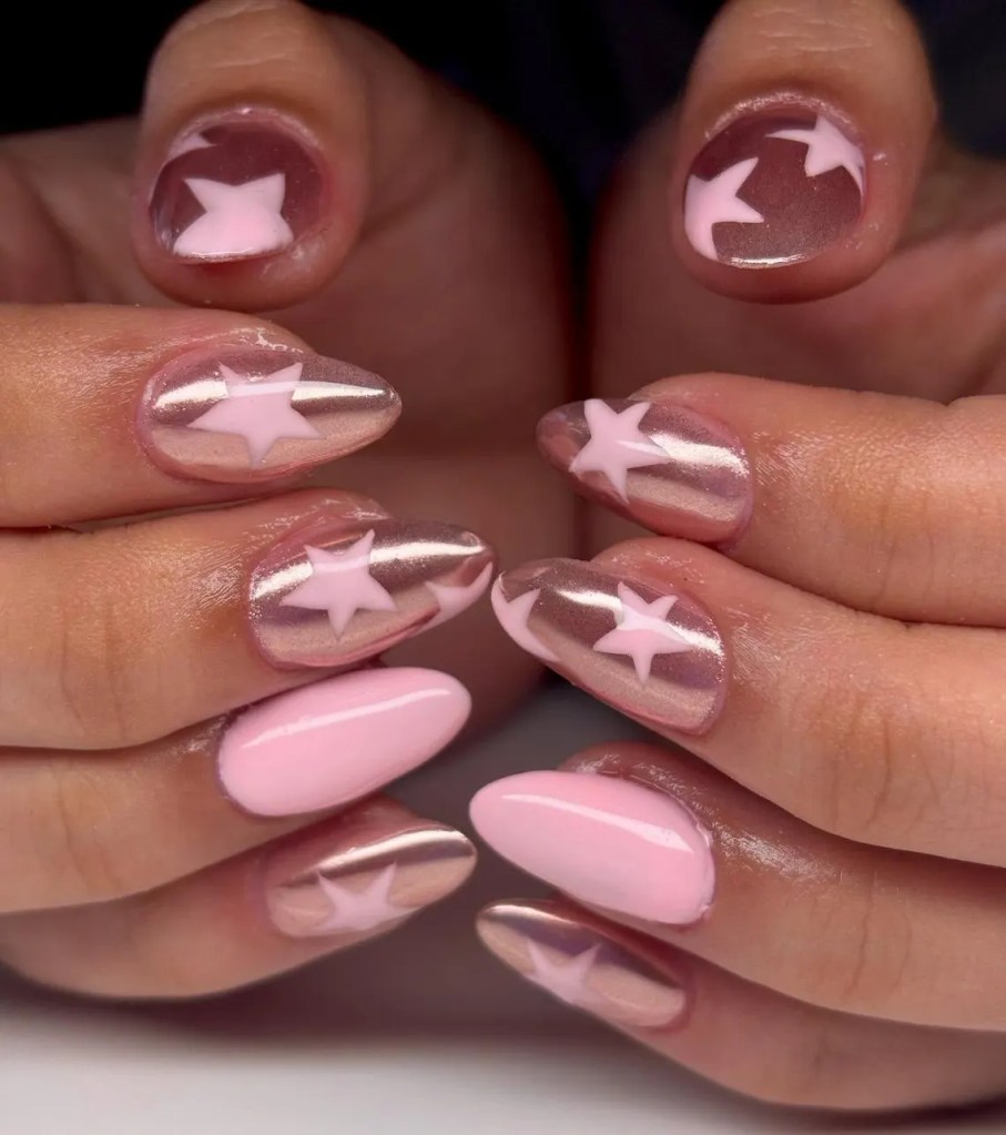 Close-up of hands displaying manicured nails with a mix of star designs, featuring glossy pink and metallic colors.