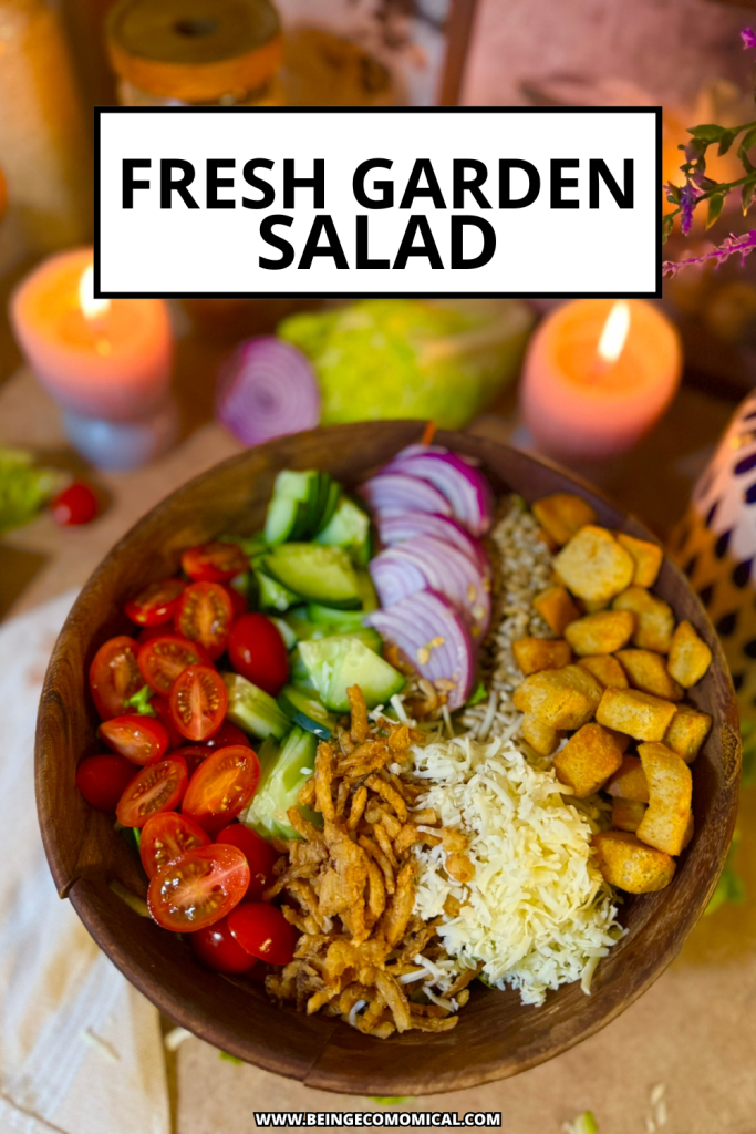 A wooden bowl filled with a fresh garden salad featuring cherry tomatoes, cucumber slices, red onion rings, crispy fried onions, shredded cheese, and croutons, set against a warm, softly lit background with candles.