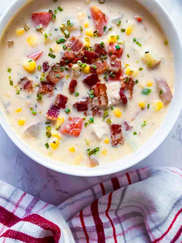 Creamy chicken corn chowder topped with crispy bacon and fresh herbs served in a rustic bowl
