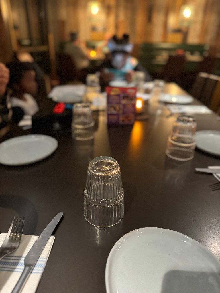 Dinner table setting with plates, forks, and glasses ready for a meal, featuring a warm ambiance.