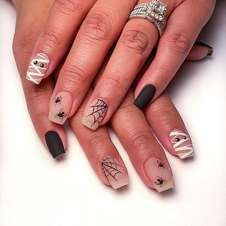 Close-up of Halloween-themed manicure featuring a mix of matte black, mummy, spider, and web designs on acrylic nails, showcasing creative seasonal nail art.