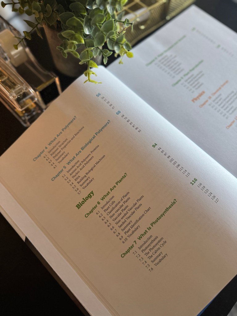An open textbook page showing the table of contents with chapters on polymers and biology, surrounded by a green plant.