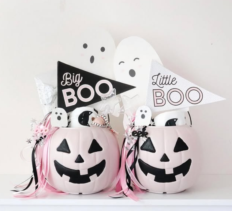 Two pastel pink pumpkin baskets labeled 'Big Boo' and 'Little Boo' are filled with festive Halloween treats, decorations, and cheerful accents, creating a whimsical and kid-friendly display.